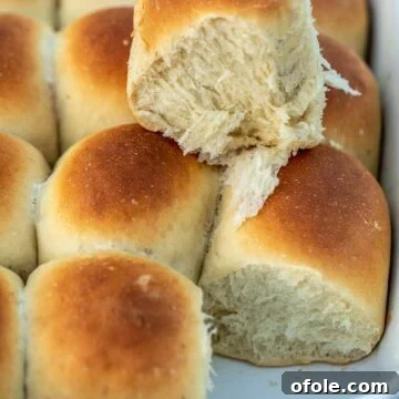 Soft and fluffy banana bread rolls in a baking pan, with one roll pulled out to show its texture.