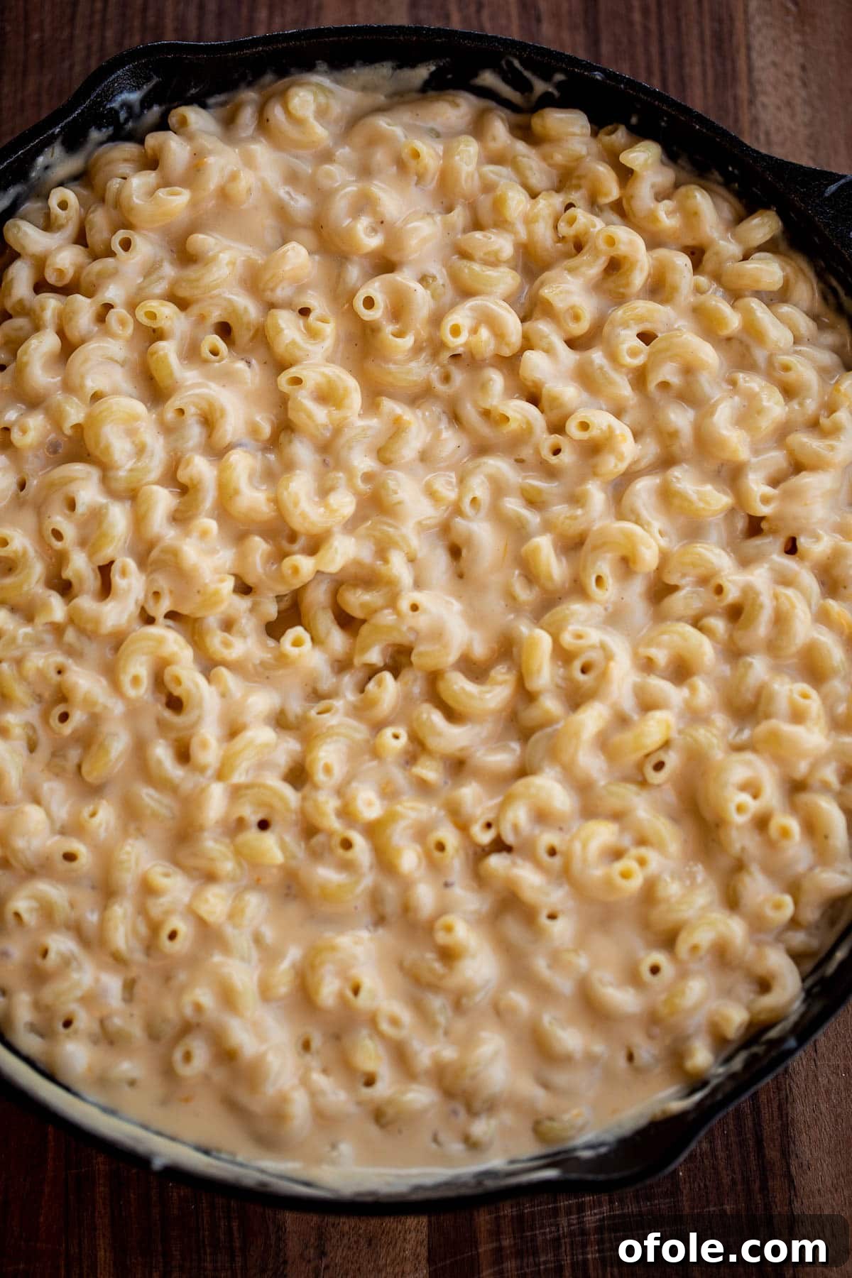 Ultimate Three-Cheese Mac and Cheese 6 Macaroni being tossed with creamy cheese sauce in a large pan