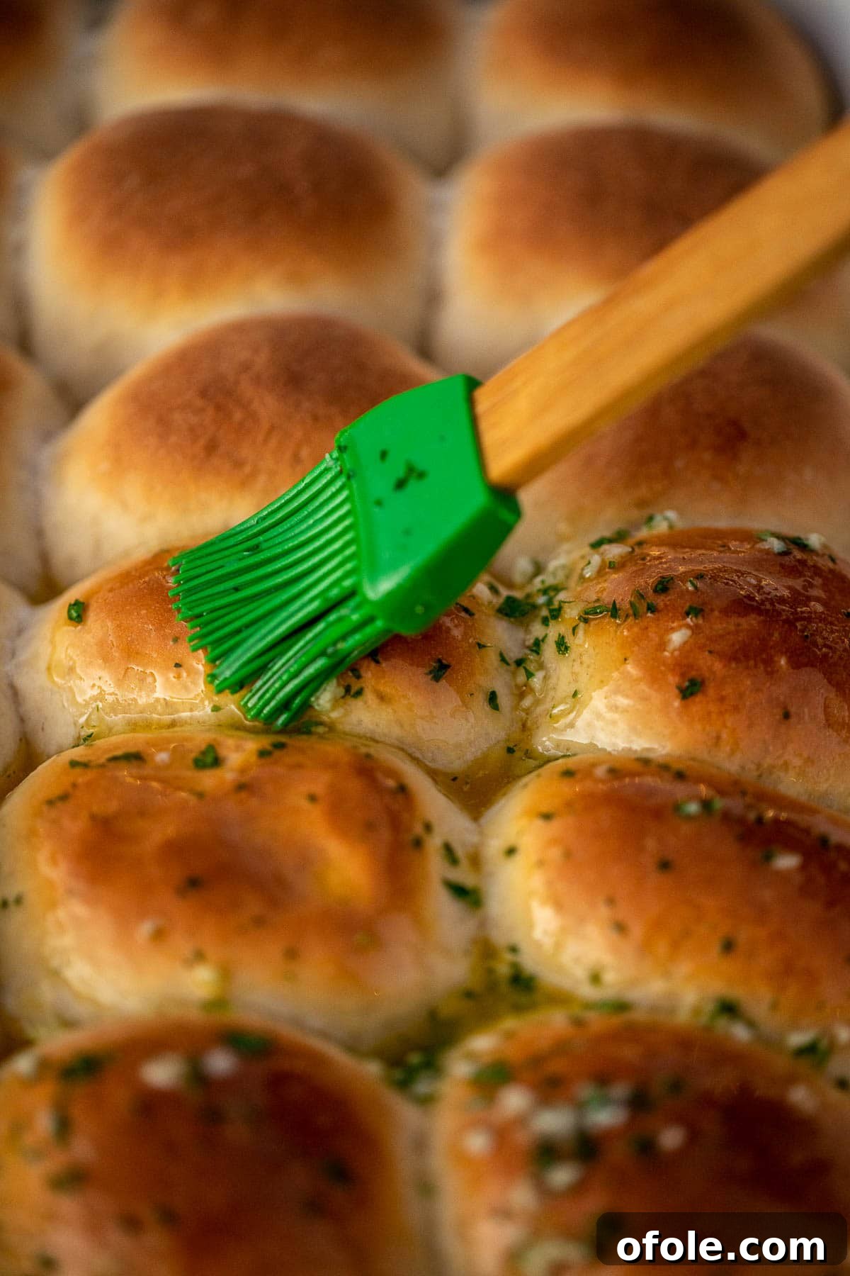 Buttery Garlic Dinner Rolls 12 A hand brushing the warm, baked dinner rolls with the savory garlic butter mixture.