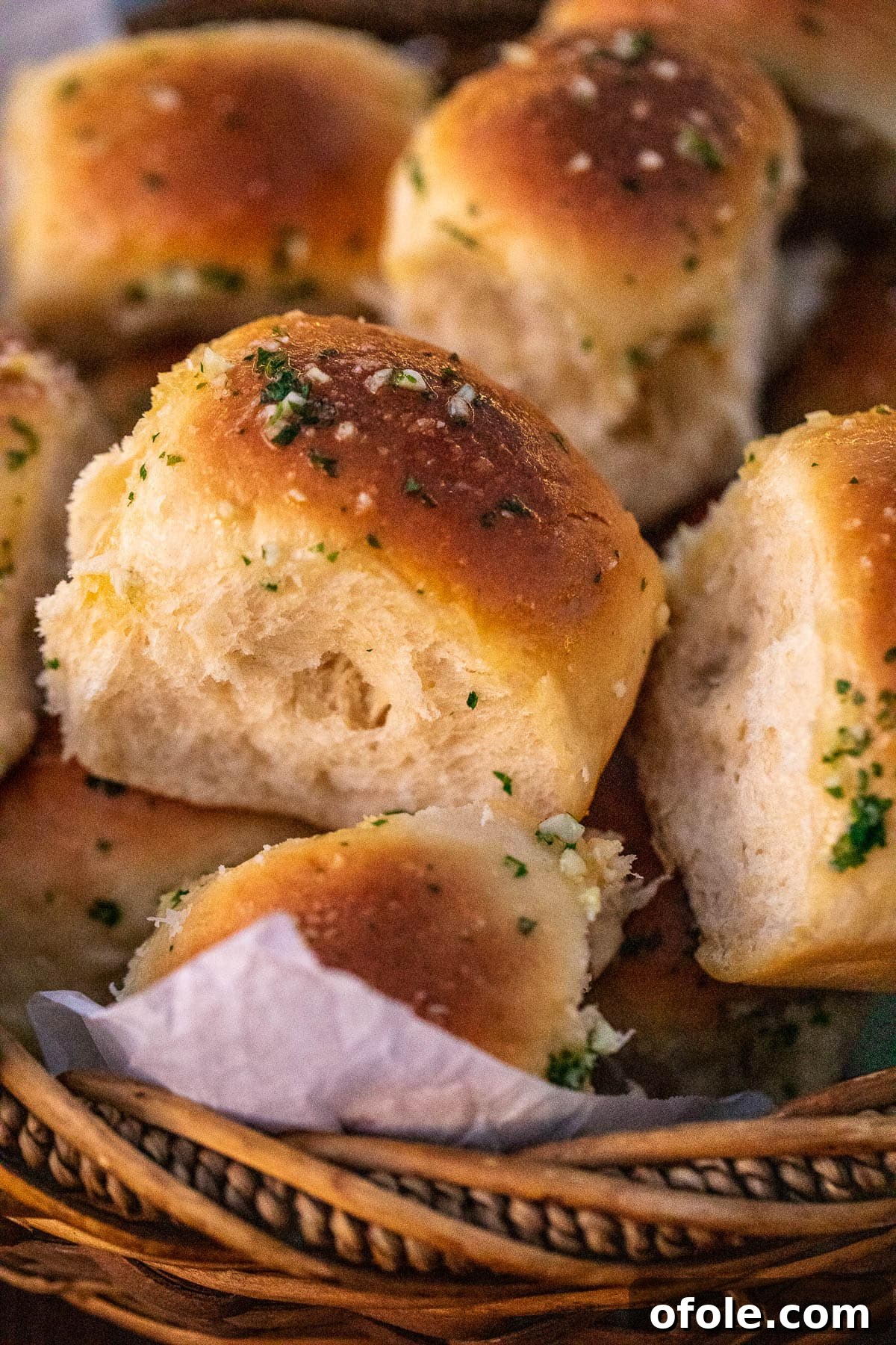 Buttery Garlic Dinner Rolls 3 Freshly baked, golden dinner rolls arranged in a rustic woven basket, ready to be served.