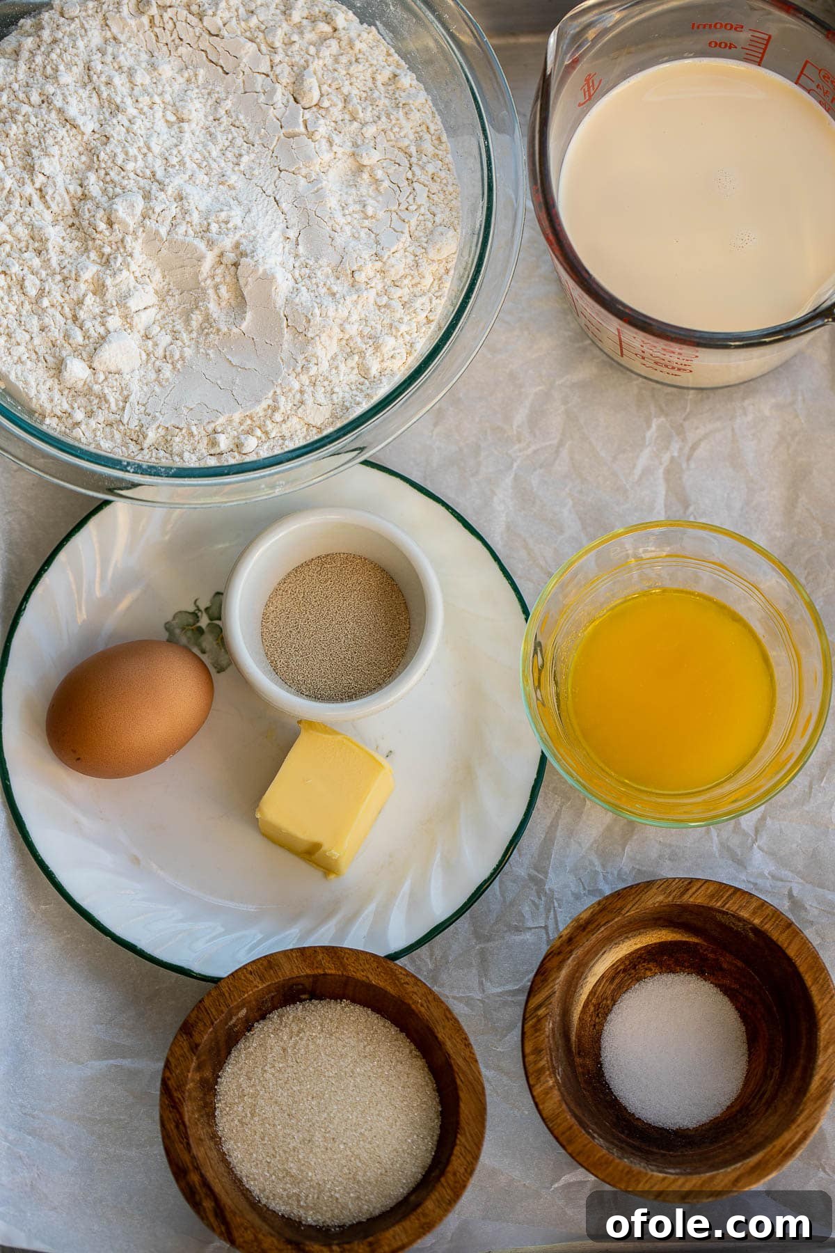 Buttery Garlic Dinner Rolls 4 A collection of ingredients for making dinner rolls, including flour, milk, butter, and eggs, neatly arranged on a counter.
