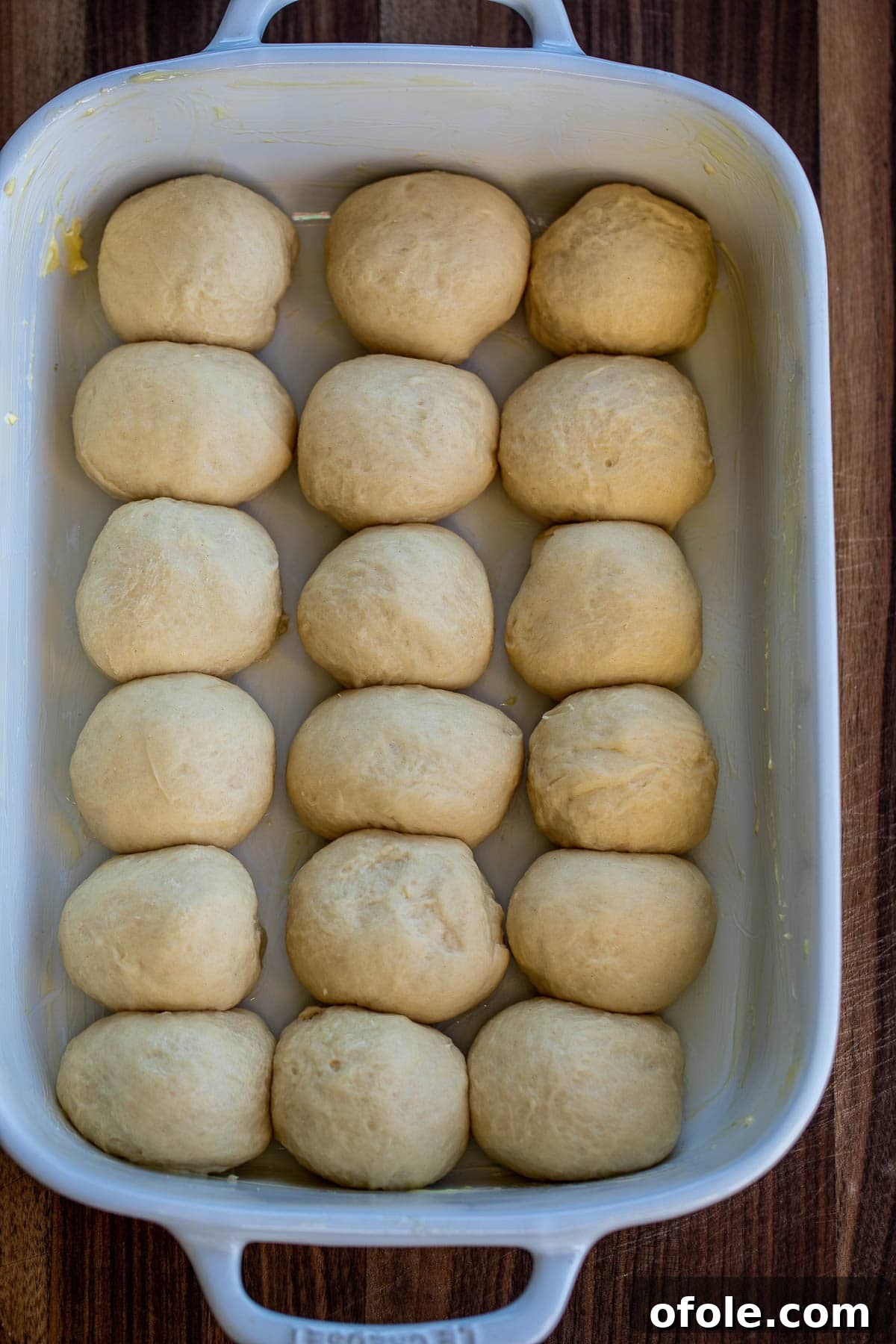 Buttery Garlic Dinner Rolls 8 Neatly shaped dinner rolls arranged in a greased baking dish, preparing for their rise.
