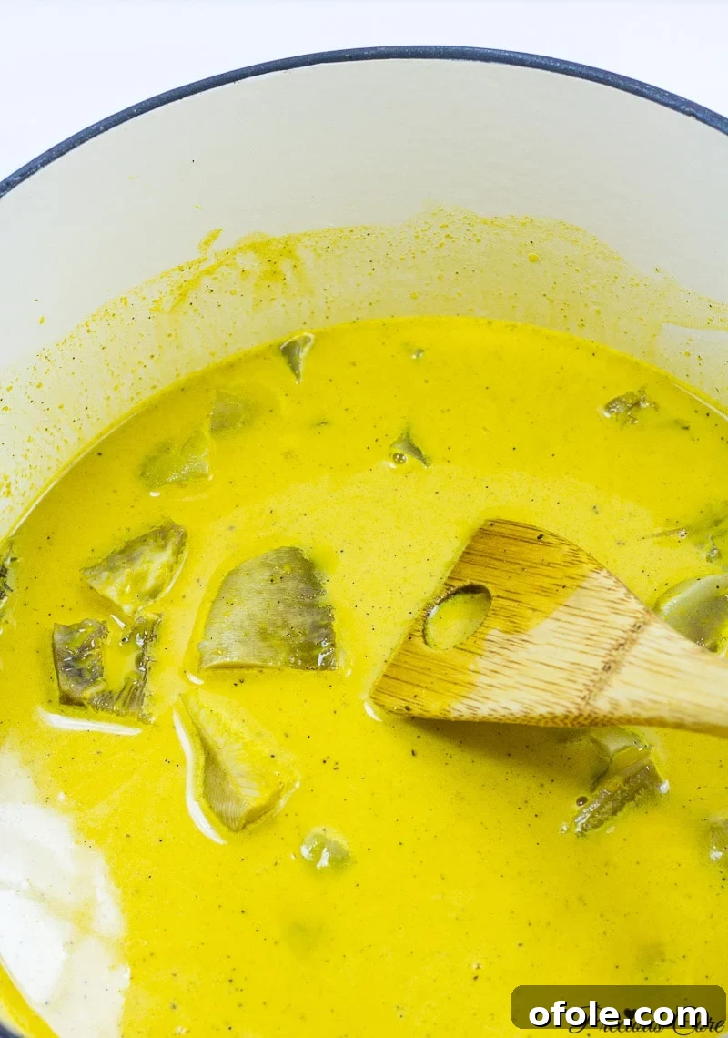Simple Steps to Perfect Achu and Yellow Soup 5 Spatula in a pot of bright yellow Achu Soup.