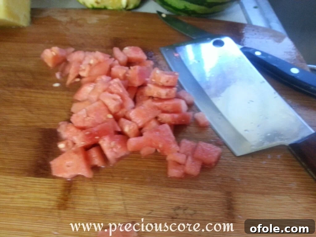 Vibrant Cameroonian Fruit Salad 9 Chopped watermelon cubes being added to the large bowl of mixed fruits