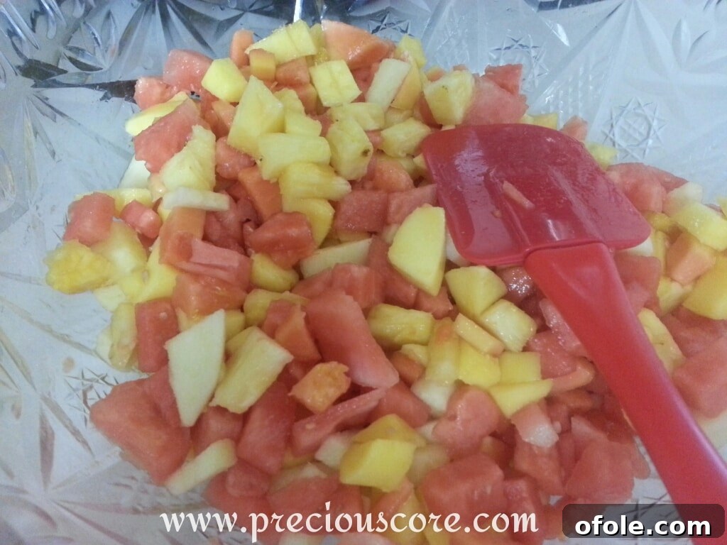 Cameroon Fruit Salad A beautifully presented Cameroonian fruit salad in a glass bowl, garnished with a mint leaf