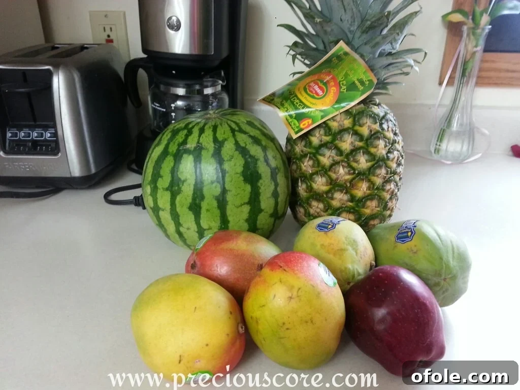 Fruit Salad Ingredients Cameroon Fresh ingredients for a tropical fruit salad: pineapple, papaya, mangoes, apple, and watermelon on a wooden board