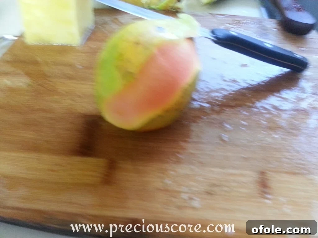 Vibrant Cameroonian Fruit Salad 3 Ripe pawpaw (papaya) being peeled with a knife on a cutting board