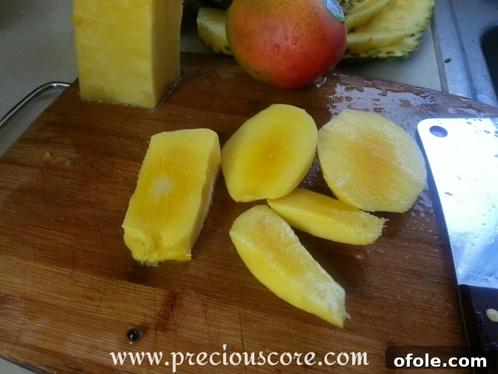 Vibrant Cameroonian Fruit Salad 6 A ripe mango being peeled and sliced around its large seed on a cutting board