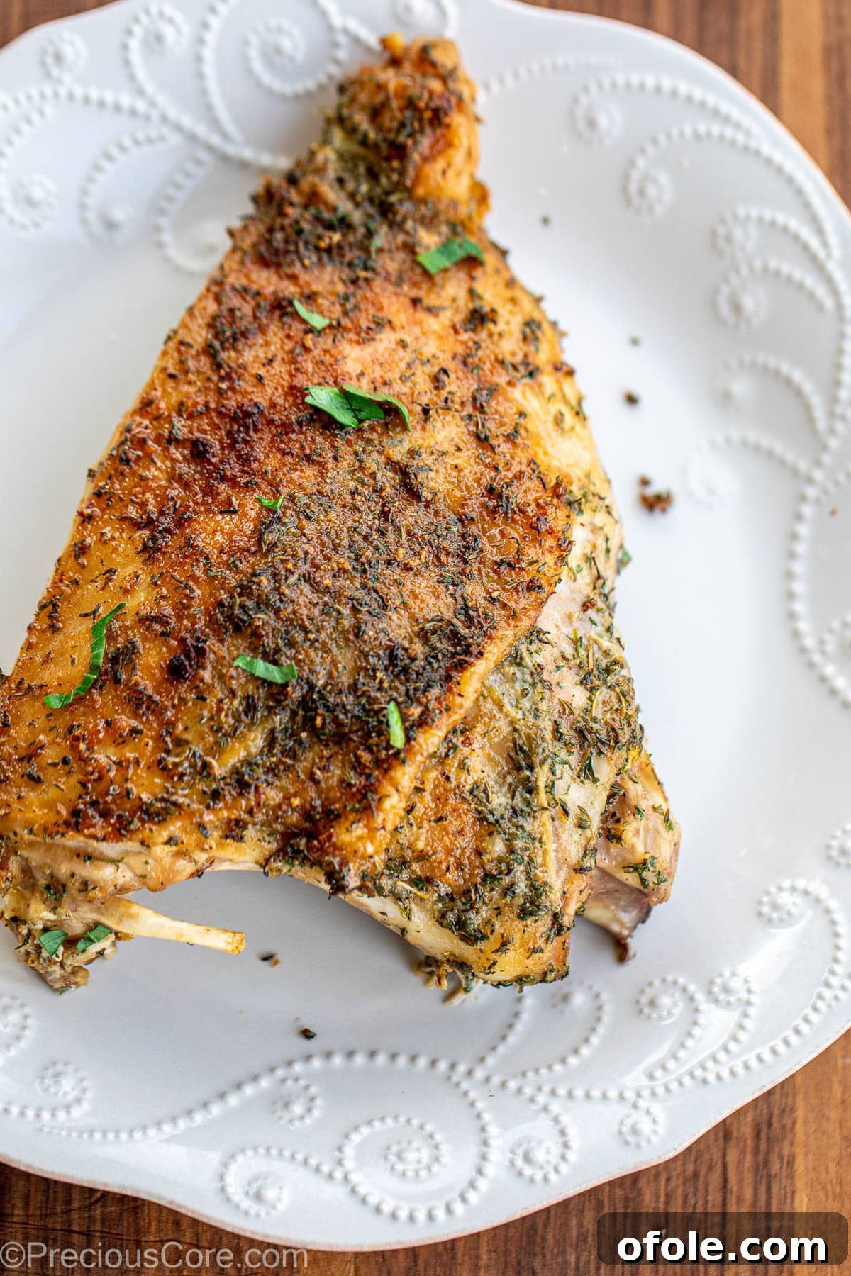 A large roasted turkey thigh on a plate, showcasing its crispy skin and golden-brown hue.