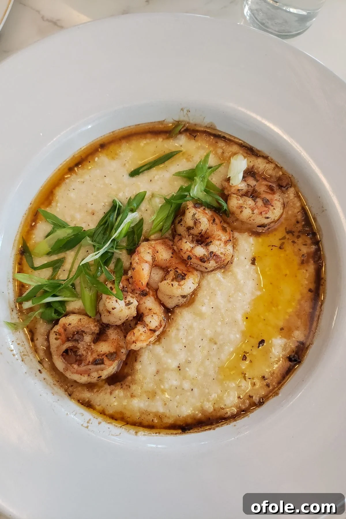Austin Bound A Family's Texas Tale 4 A beautifully plated dish of shrimp and grits, garnished with fresh herbs, showcasing a delicious meal from an Austin restaurant.