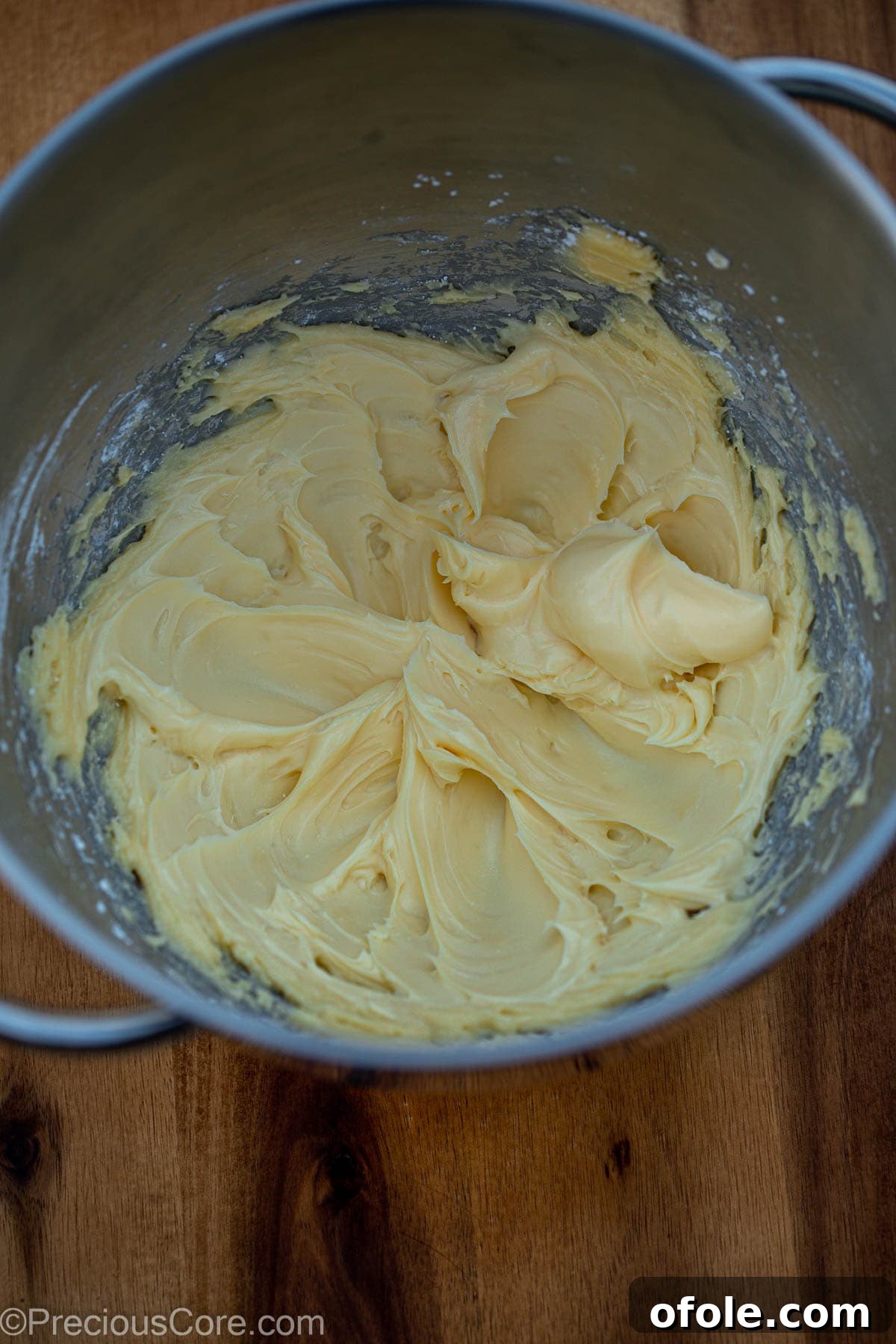 Softened butter and powdered sugar being creamed together in the bowl of a stand mixer with a paddle attachment.