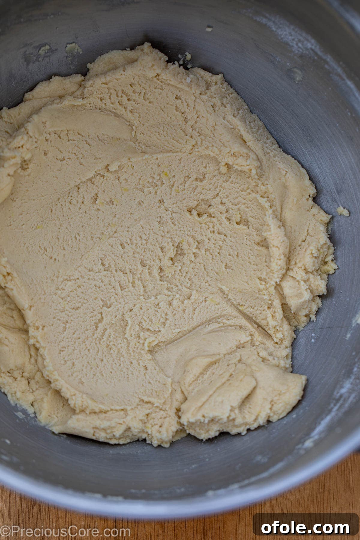 A bowl filled with freshly prepared shortbread cookie dough, featuring visible specks of lemon zest.