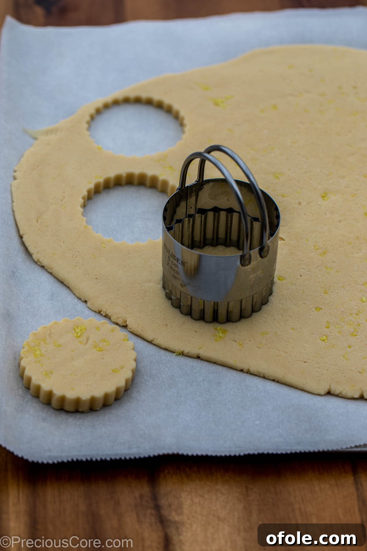 A 2-inch round cookie cutter positioned on chilled shortbread dough, ready for cutting.
