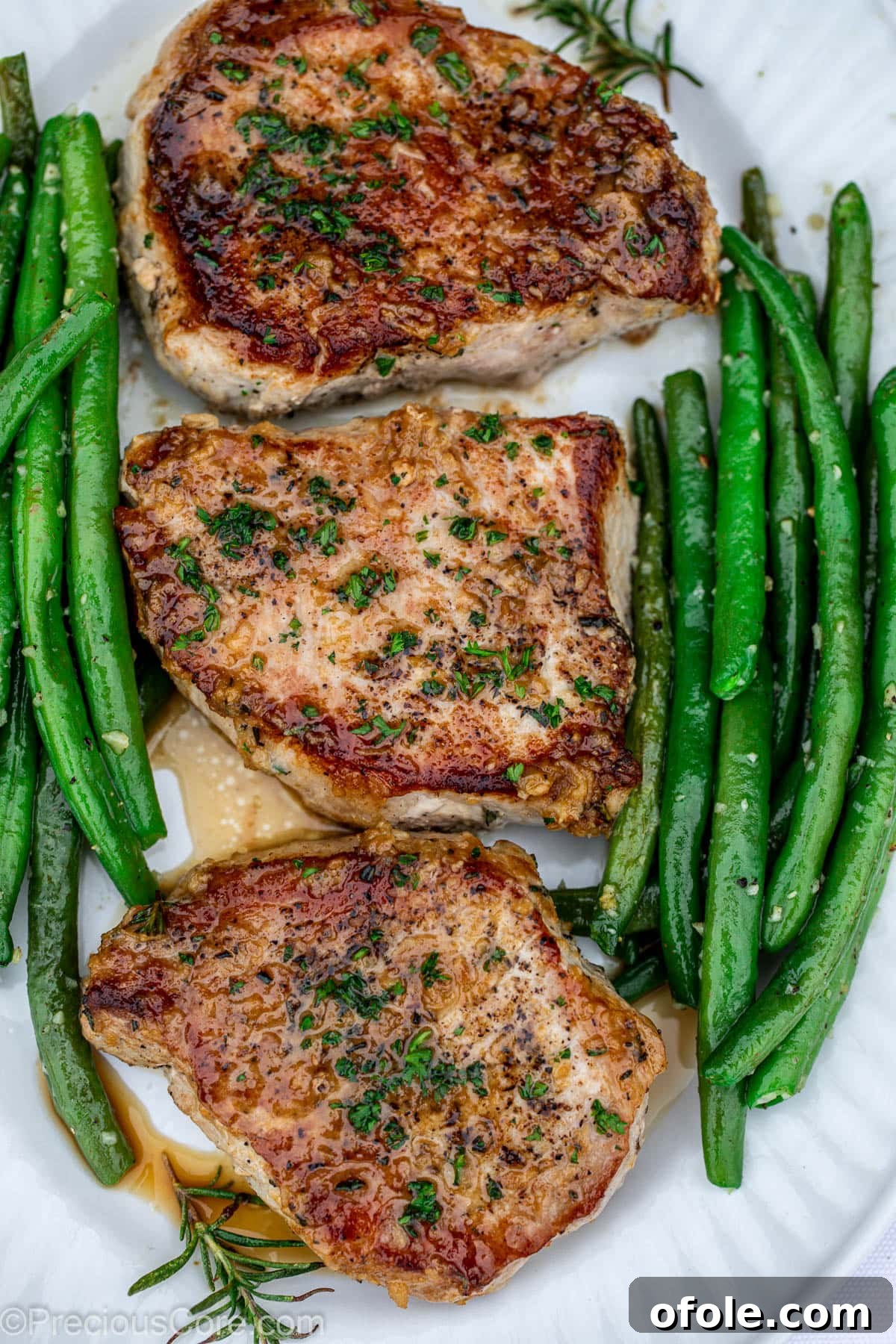 Pan Seared Pork Chops alongside a generous serving of garlic butter green beans.