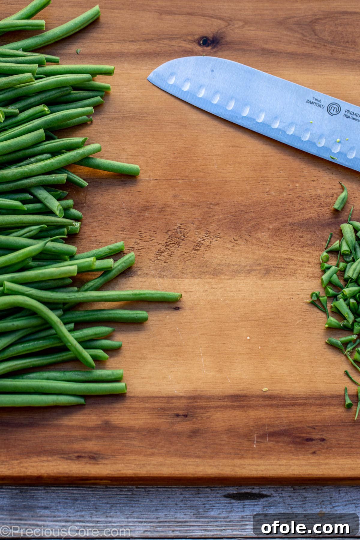 Cutting green beans on chopping board, removing stem ends.