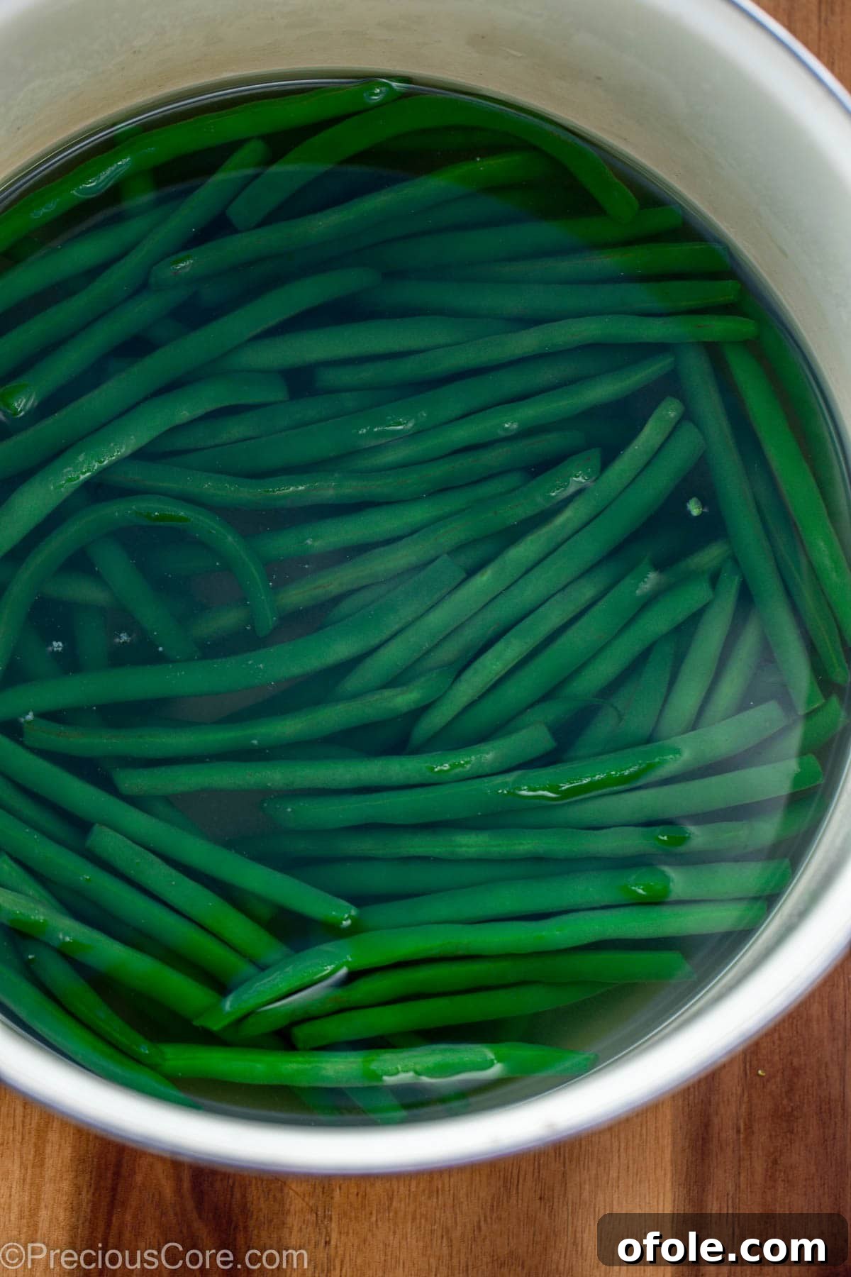 Green beans in a pot of hot boiling water with steam rising.