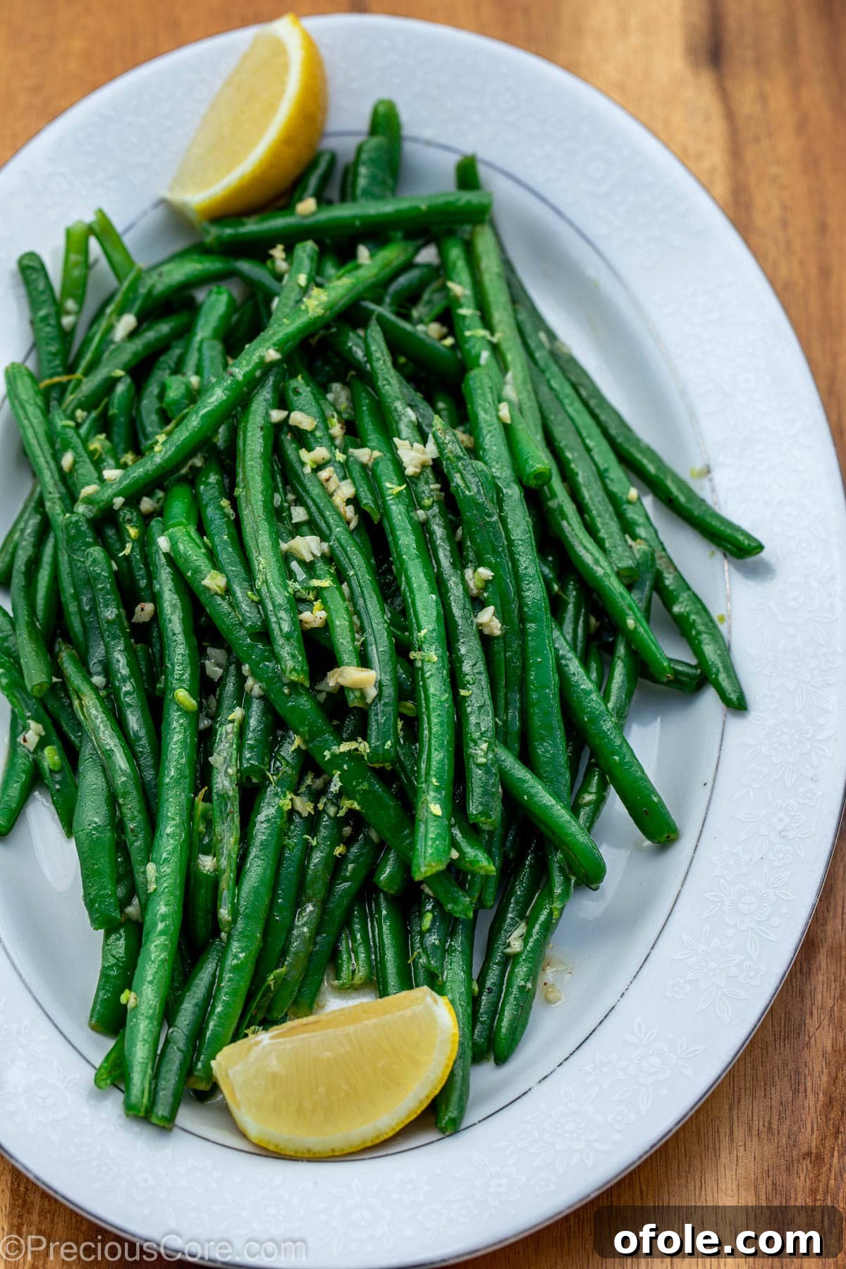 Garlic butter green beans served on a tray with fresh lemon slices for garnish.