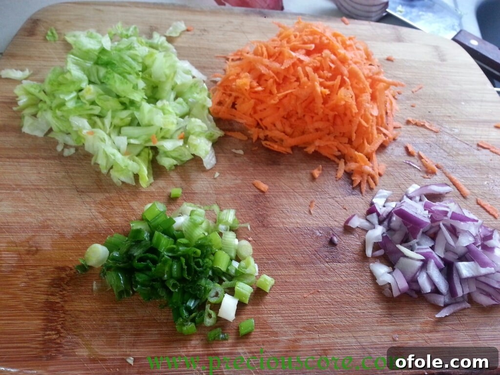 Chopped lettuce, onions, and shredded carrots on a cutting board