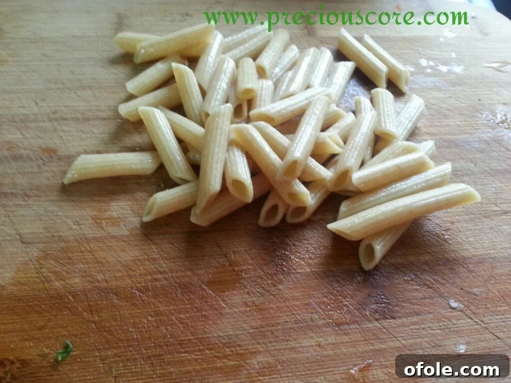 Cooked macaroni being rinsed with cool water in a colander