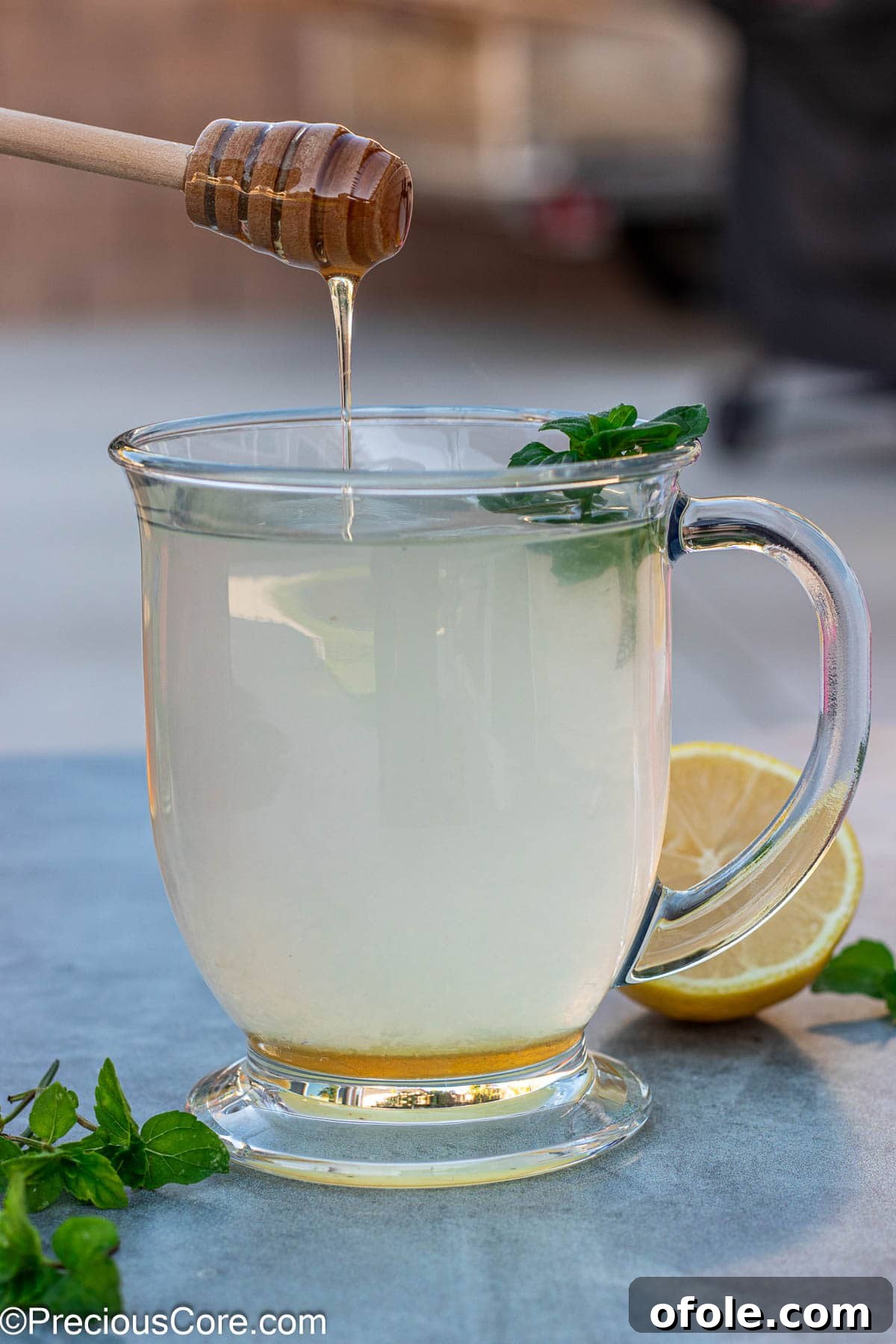 Sweet Citrus Soother 2 Honey dipper dripping honey into a cup of honey lemon tea.