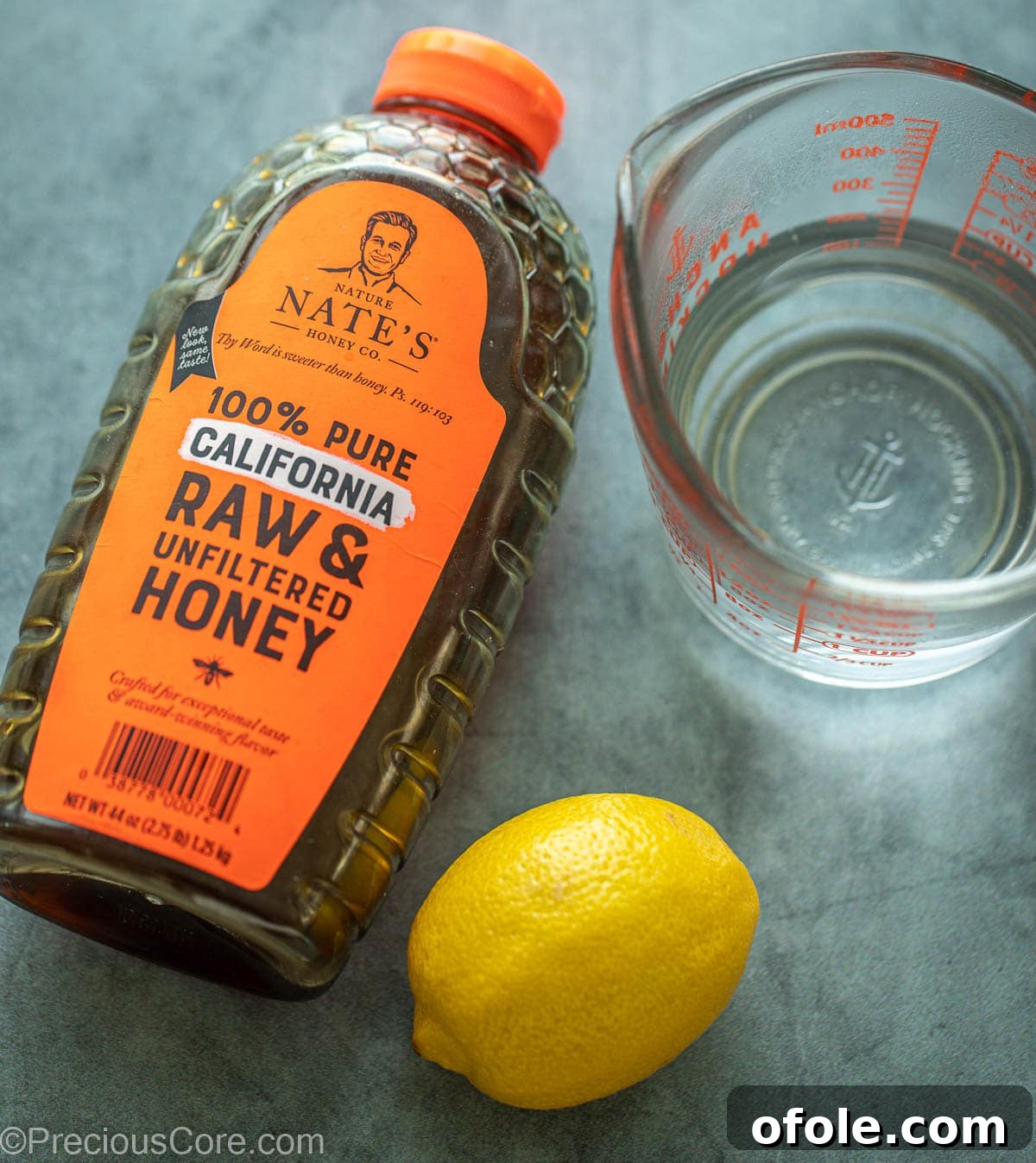 Sweet Citrus Soother 3 Container of honey, a lemon and water in a cup.
