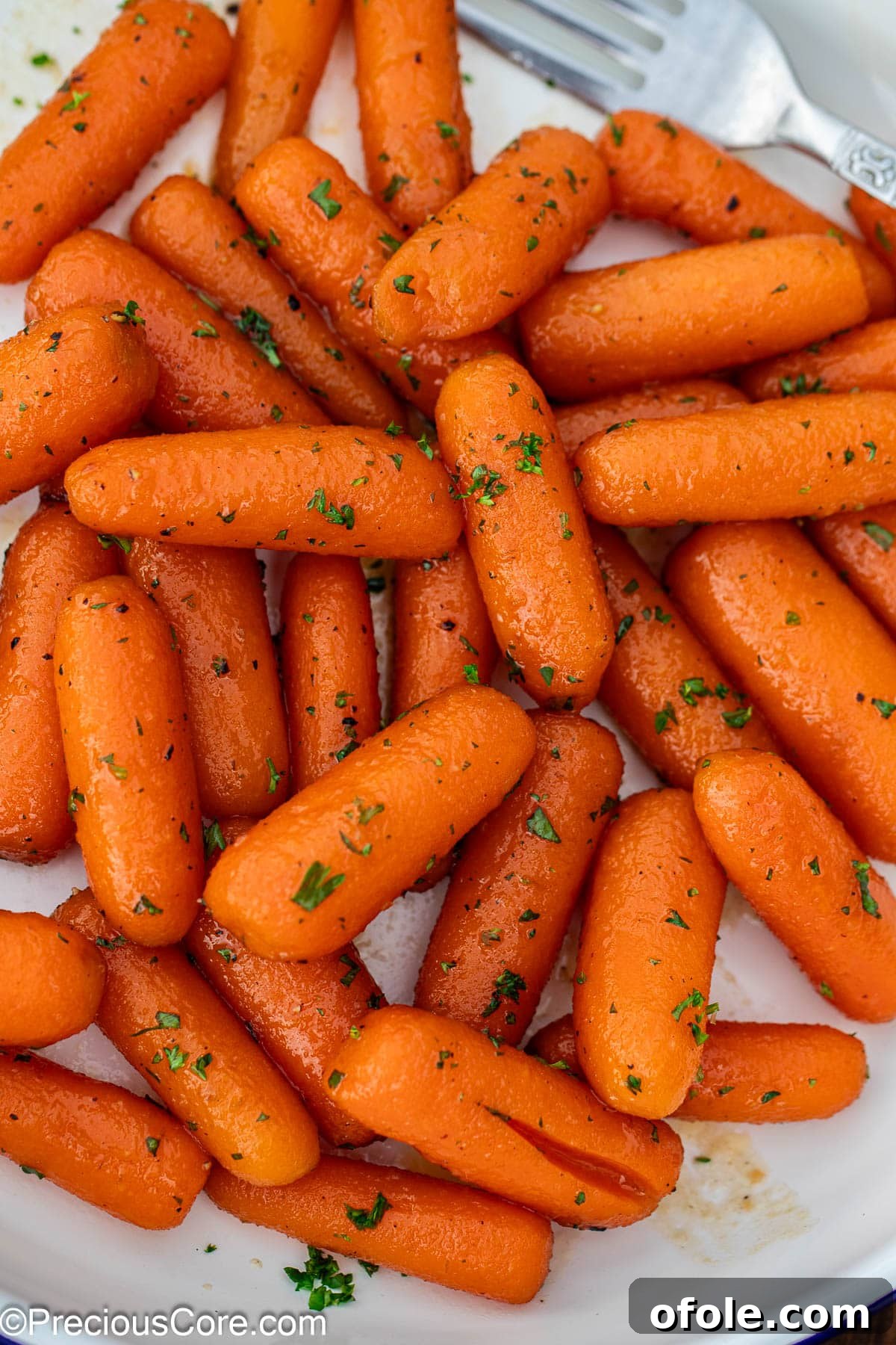Brown sugar honey glazed carrots on a plate, garnished with fresh herbs.