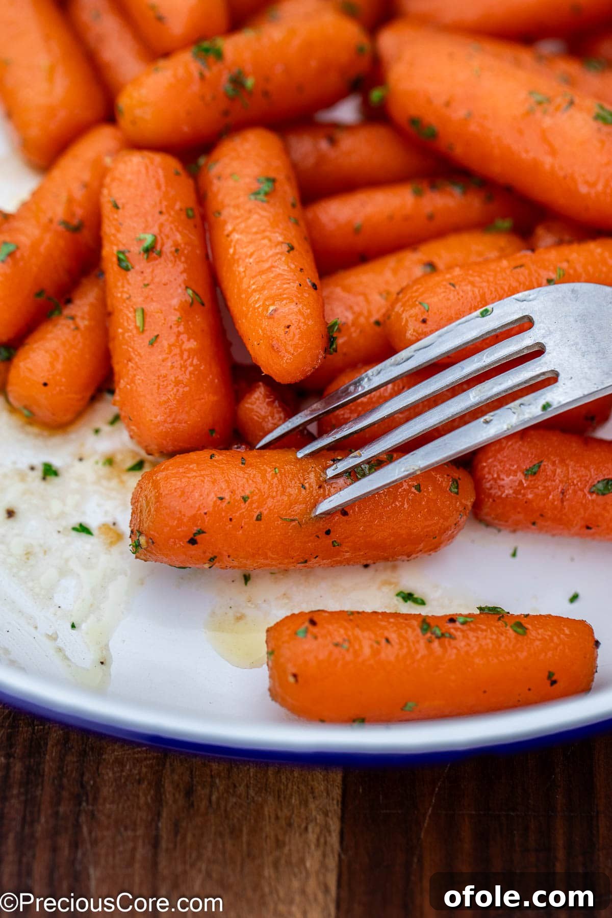 A fork piercing into a perfectly cooked, glazed carrot, showing its tenderness.
