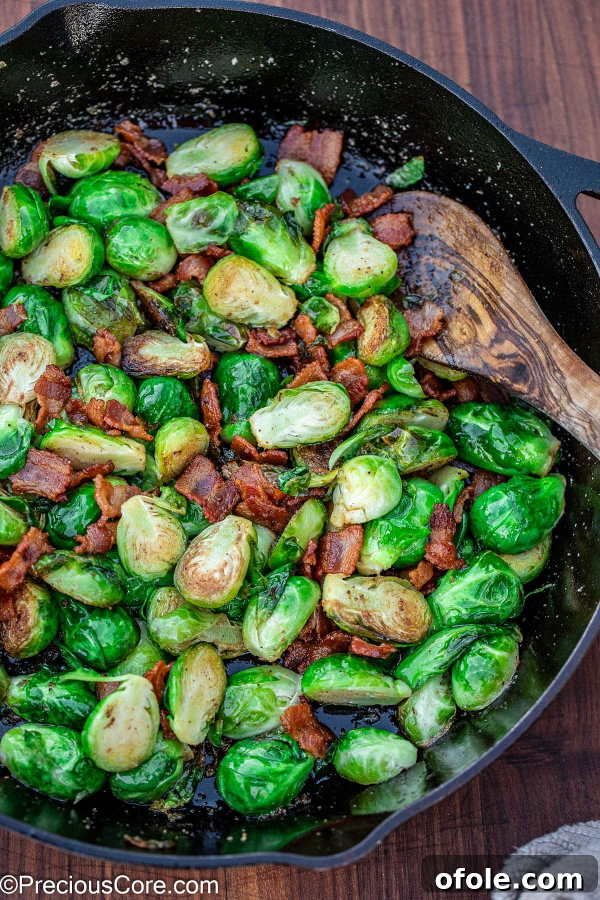 Pan-fried Brussels sprouts with crispy bacon in a black skillet, perfectly cooked and ready to serve.