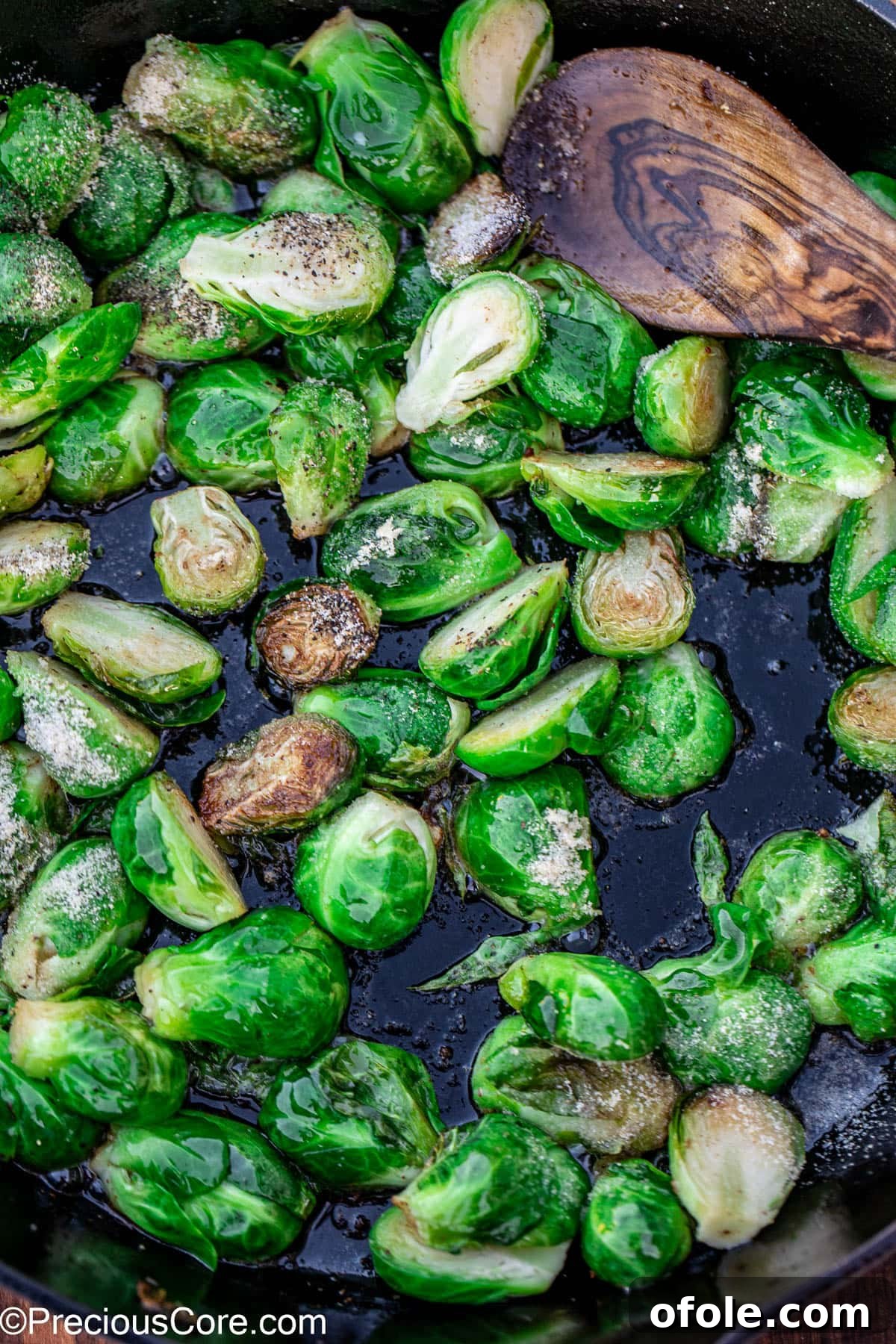 Bright green Brussels sprouts sprinkled with salt and pepper in a skillet, ready to cook.