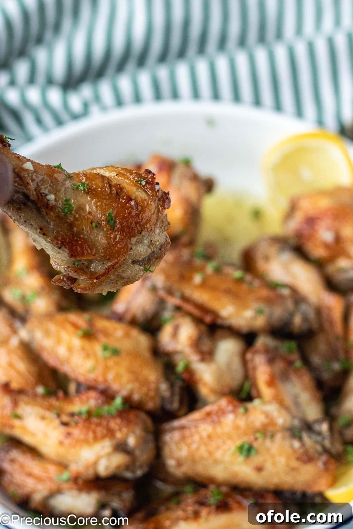 Garlic Gold Wings 3 A hand reaches for a perfectly cooked garlic butter chicken wing, highlighting its golden crispiness.