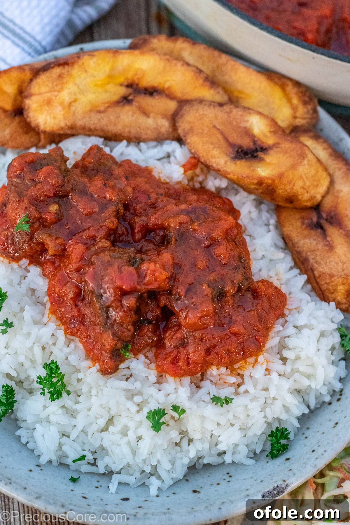 Soulful Nigerian Beef Stew 11 A bowl with steamed rice, vibrant tomato stew, and golden fried plantains, a complete Nigerian meal.