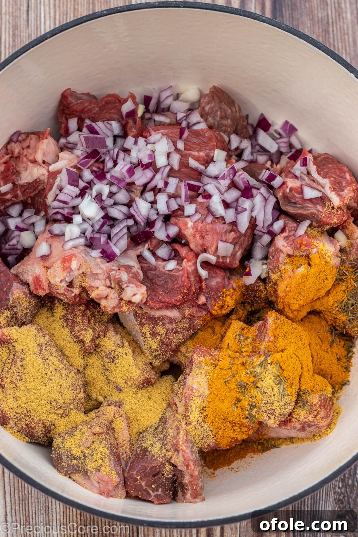Soulful Nigerian Beef Stew 4 Raw beef with diced onions and seasoning powder over it in a pot, ready for boiling.