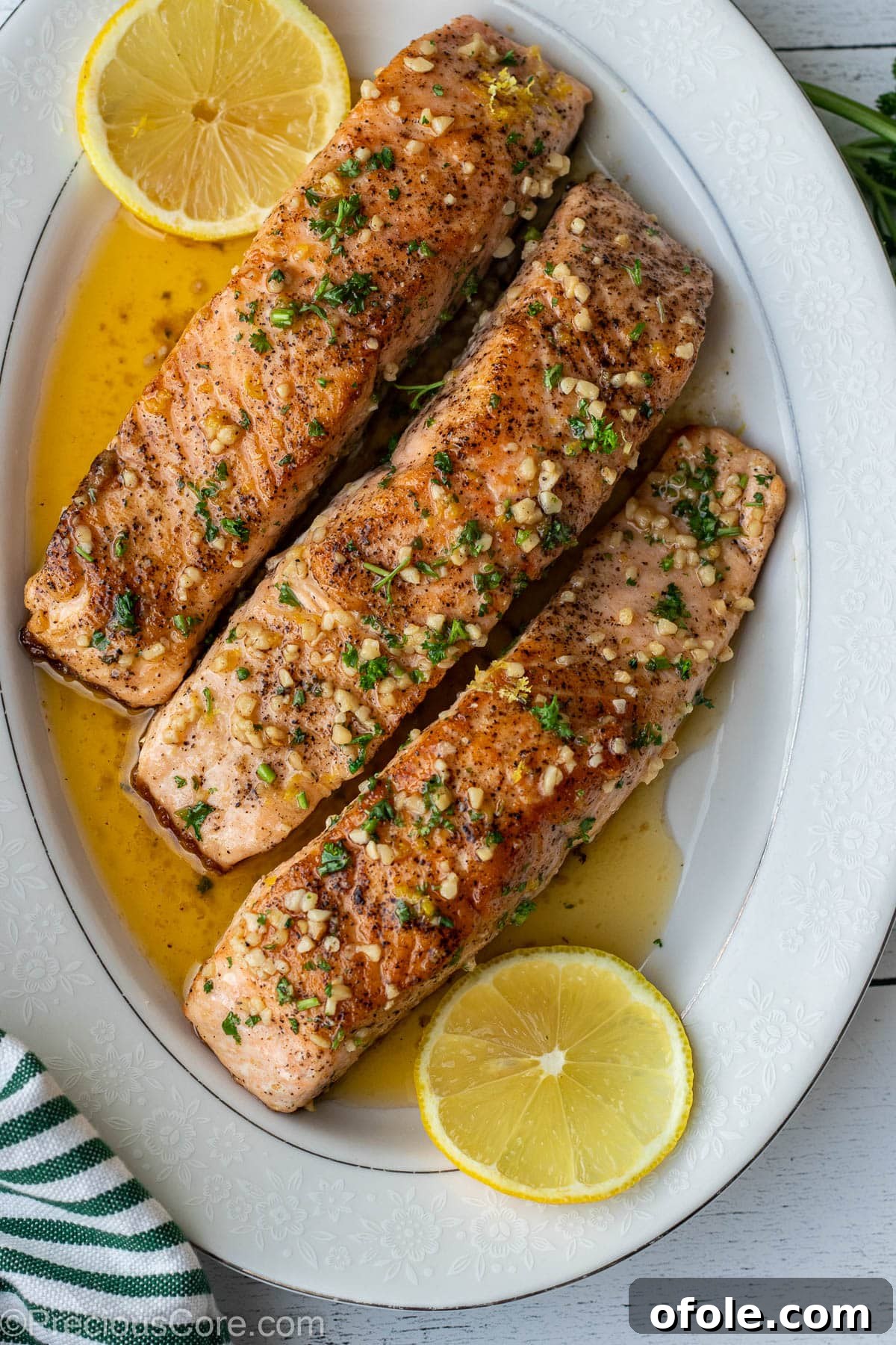 A serving platter of golden-brown lemon butter salmon fillets, showcasing their perfectly cooked, flaky texture.