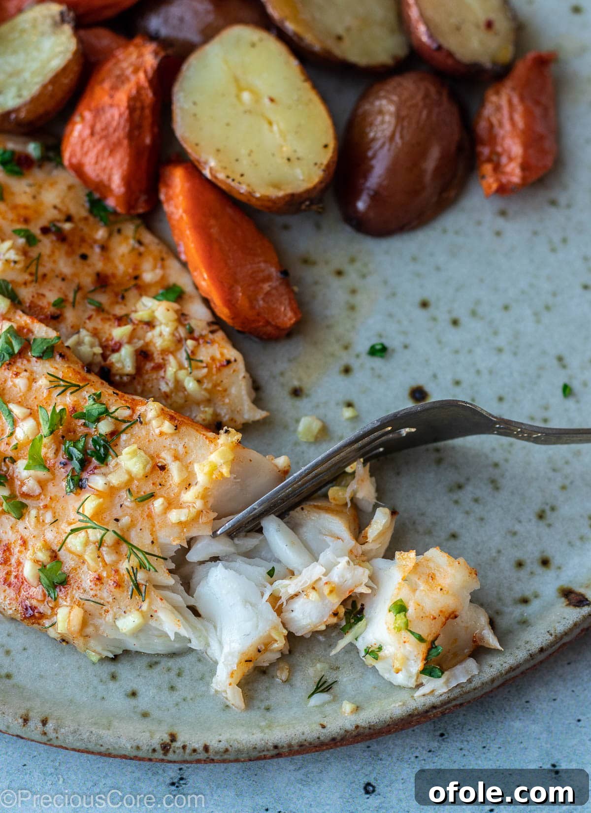 Garlic Butter Infused Tilapia 9 A serving of perfectly flaky fish on a white plate, showcasing its tender texture.