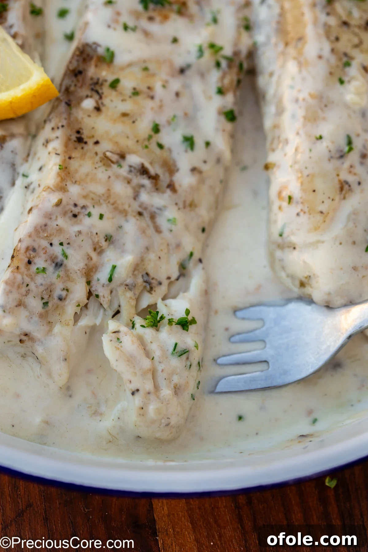 Velvety White Fish 3 Fork delicately scooping a piece of cooked fish from the pan, highlighting its tender texture and the creamy white sauce.
