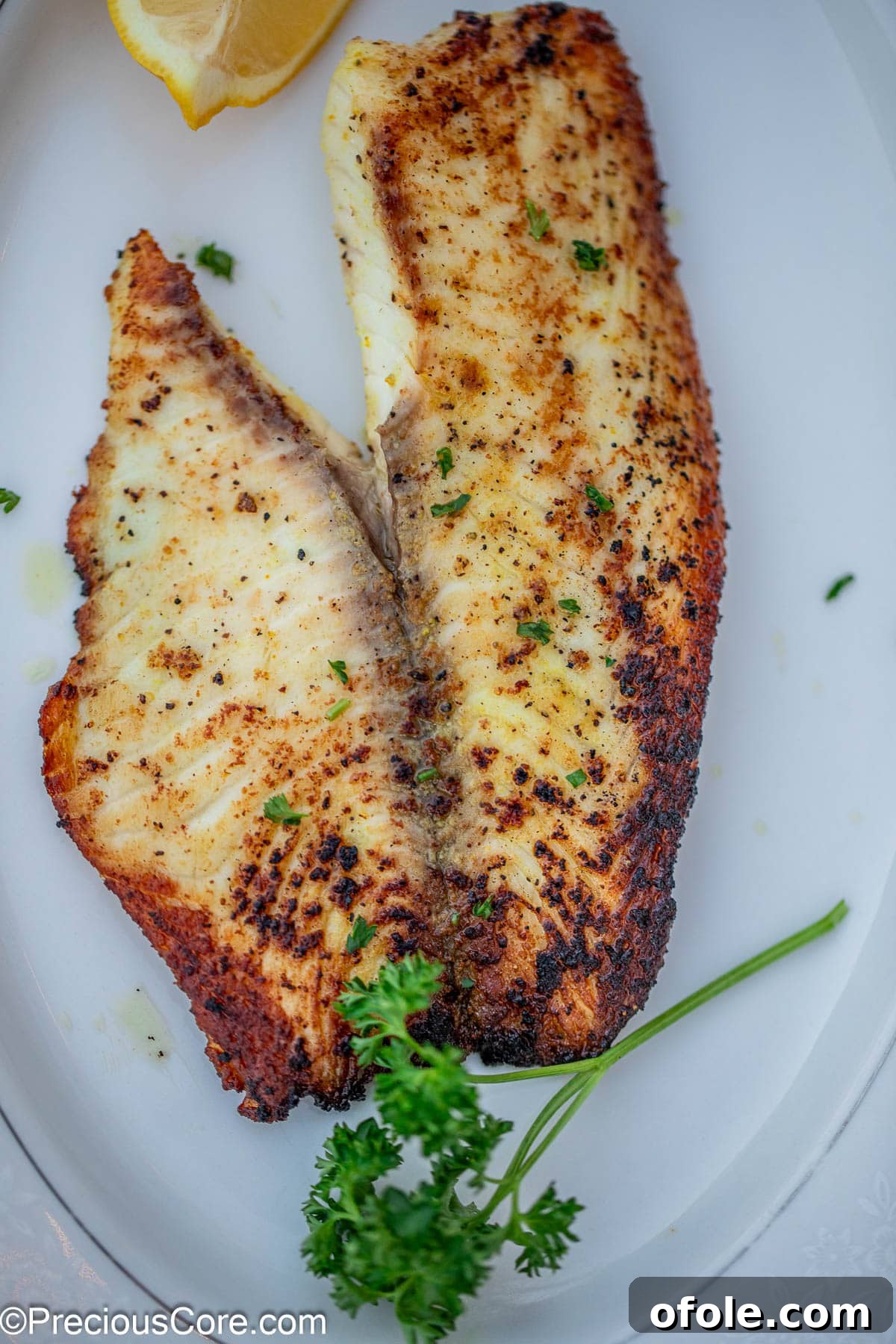 A cooked fish fillet elegantly garnished with fresh, minced parsley, showcasing its appeal.