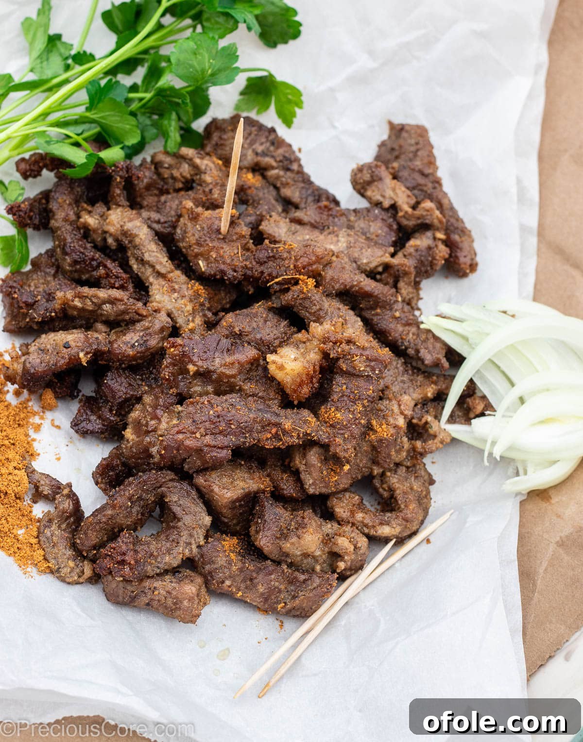 Cameroonian Soya Snack 2 Flavorful Cameroonian grilled meat served on parchment paper with fresh onions and a sprinkle of soya pepper.