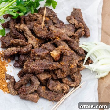 Cameroonian grilled meat served on parchment paper with fresh onions and a sprinkle of soya pepper.