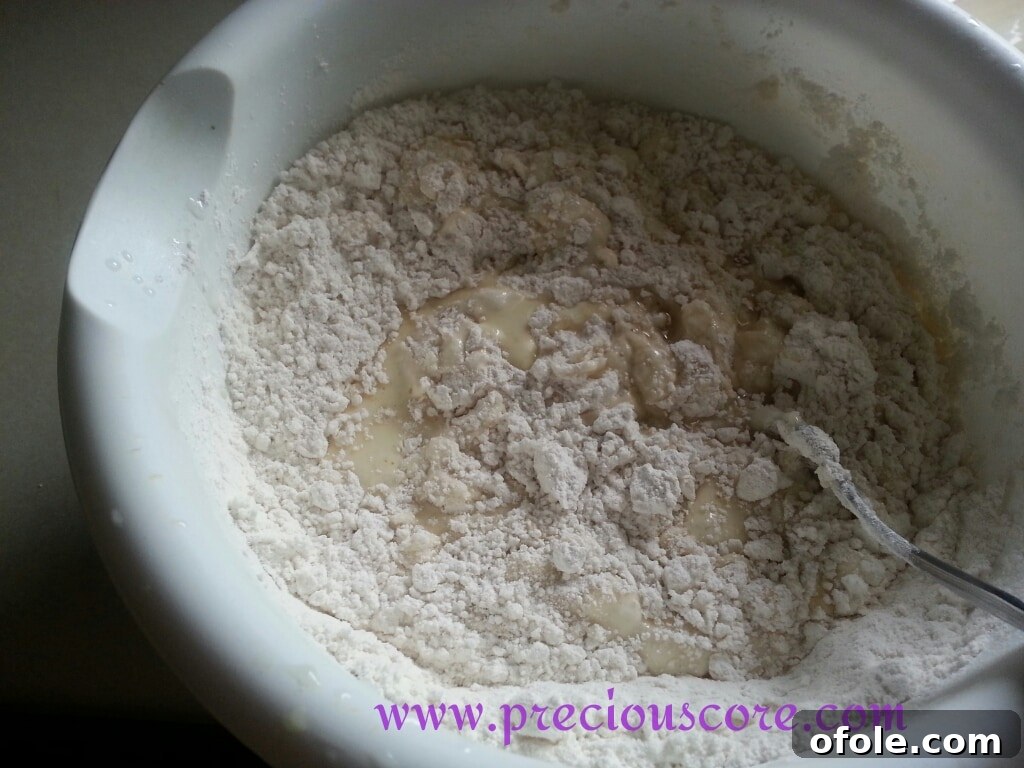 Beaten eggs and coconut milk being poured into the bowl of dry ingredients.