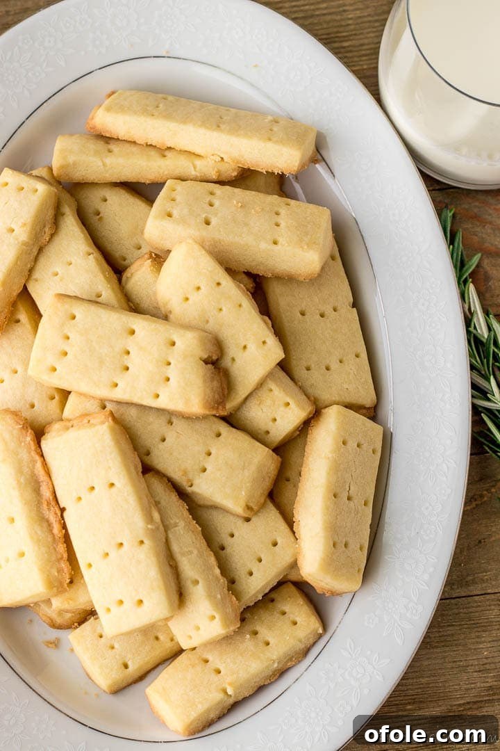 Perfect Buttery Shortbread From Scratch 2 Golden shortbread cookies arranged beautifully on a platter, with a glass of milk on the side, inviting a delightful tasting experience.