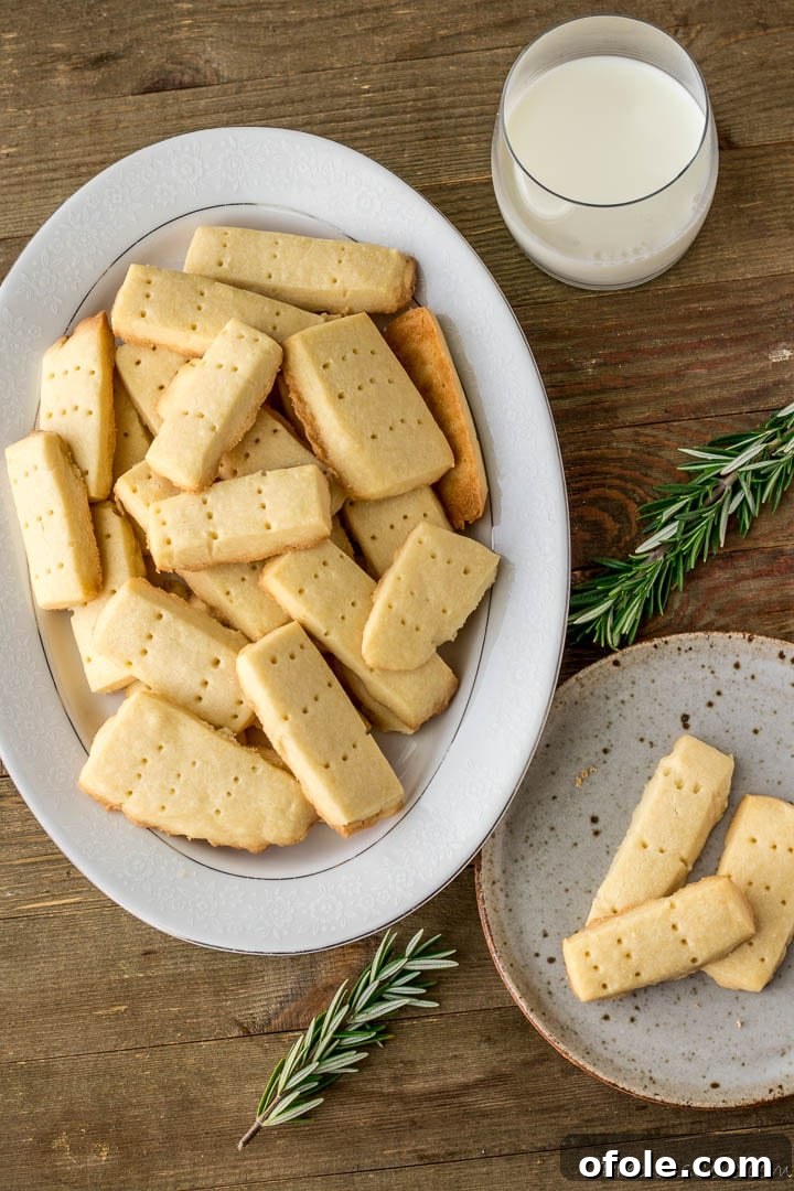 Perfect Buttery Shortbread From Scratch 16 A selection of homemade shortbread cookies presented on a plate and a larger platter, accompanied by a glass of milk, creating a warm and inviting scene.