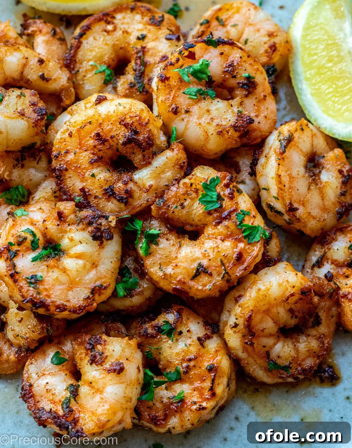 Pan Seared Shrimp on a plate, garnished with fresh herbs and lemon wedges.