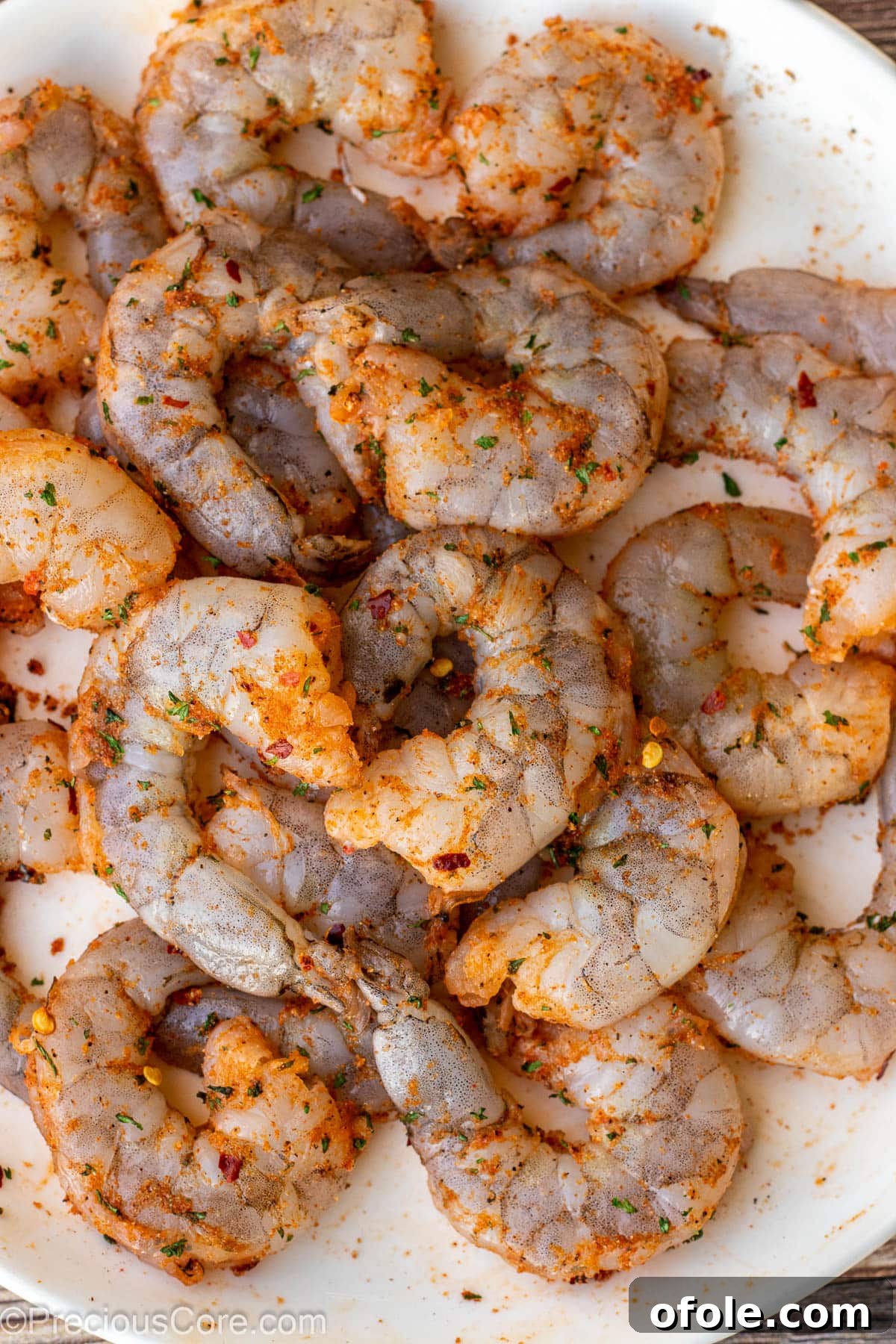 Sizzling Garlic Shrimp 4 Raw seasoned shrimp on a white plate, ready to be cooked.