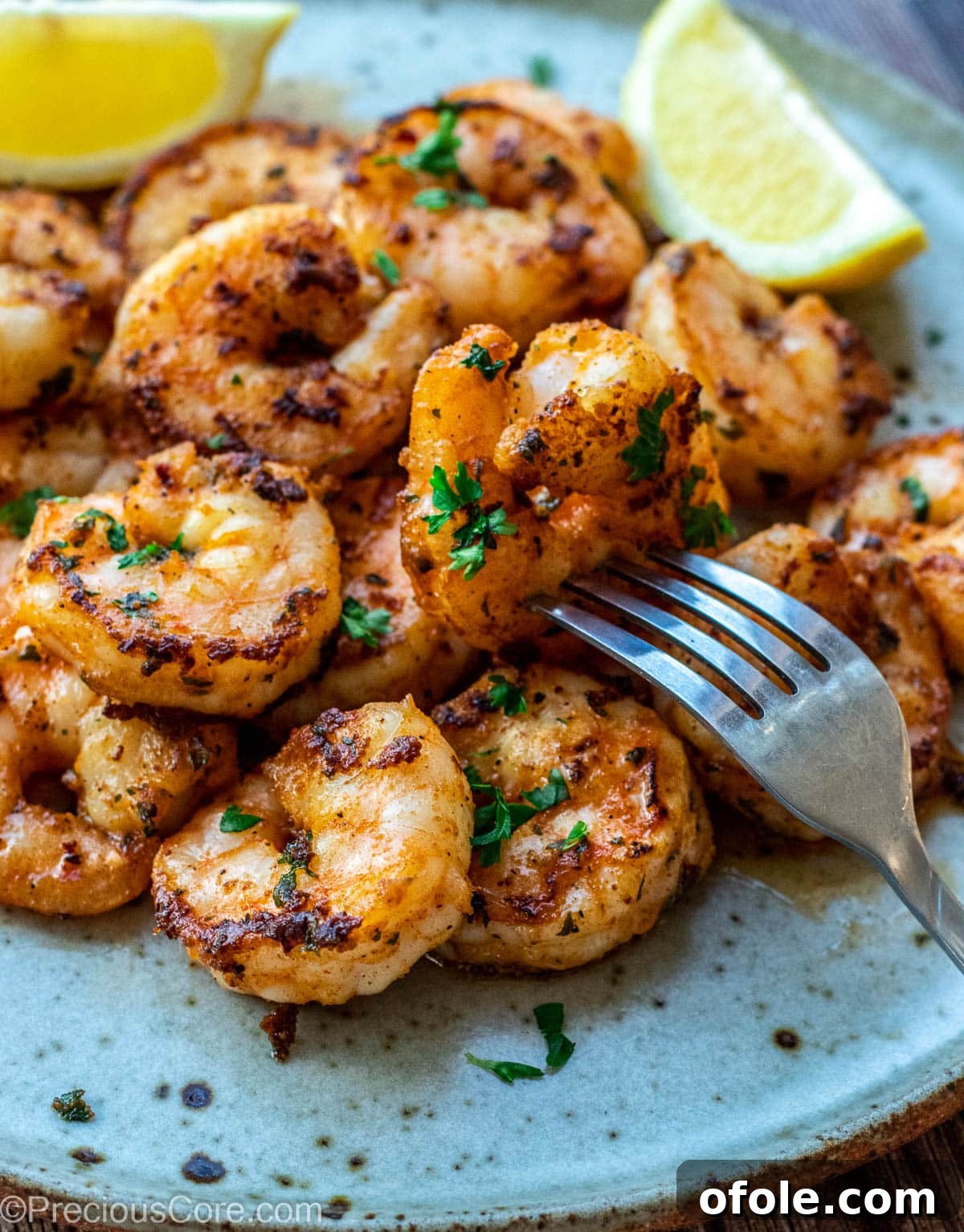 Sizzling Garlic Shrimp 7 Shrimp on a plate with lemon wedges, ready to be enjoyed.
