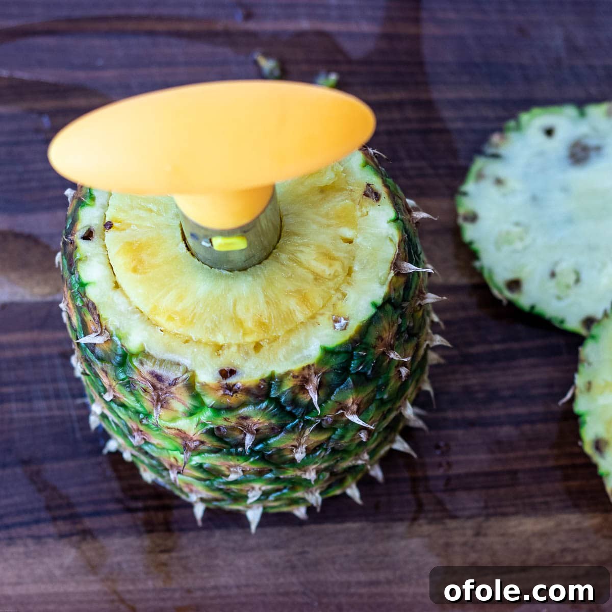 A pineapple with a pineapple corer inserted, demonstrating preparation for fresh pineapple rings.