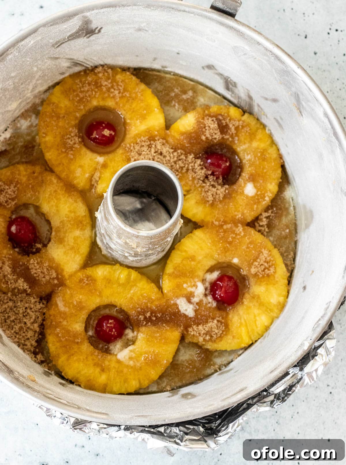 A baking pan meticulously covered at the bottom with pineapple rings, maraschino cherries, brown sugar, and melted butter, ready for the cake batter.