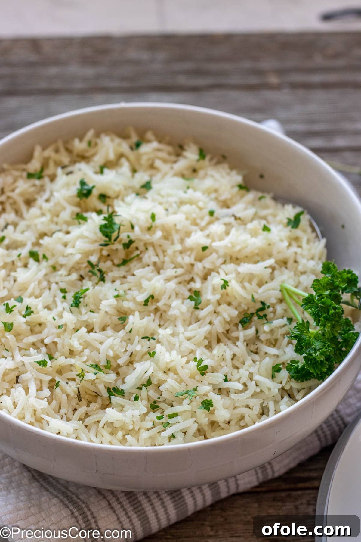 A bowl of garlic herb rice topped with minced fresh parsley, ready to be served as a delicious side dish.
