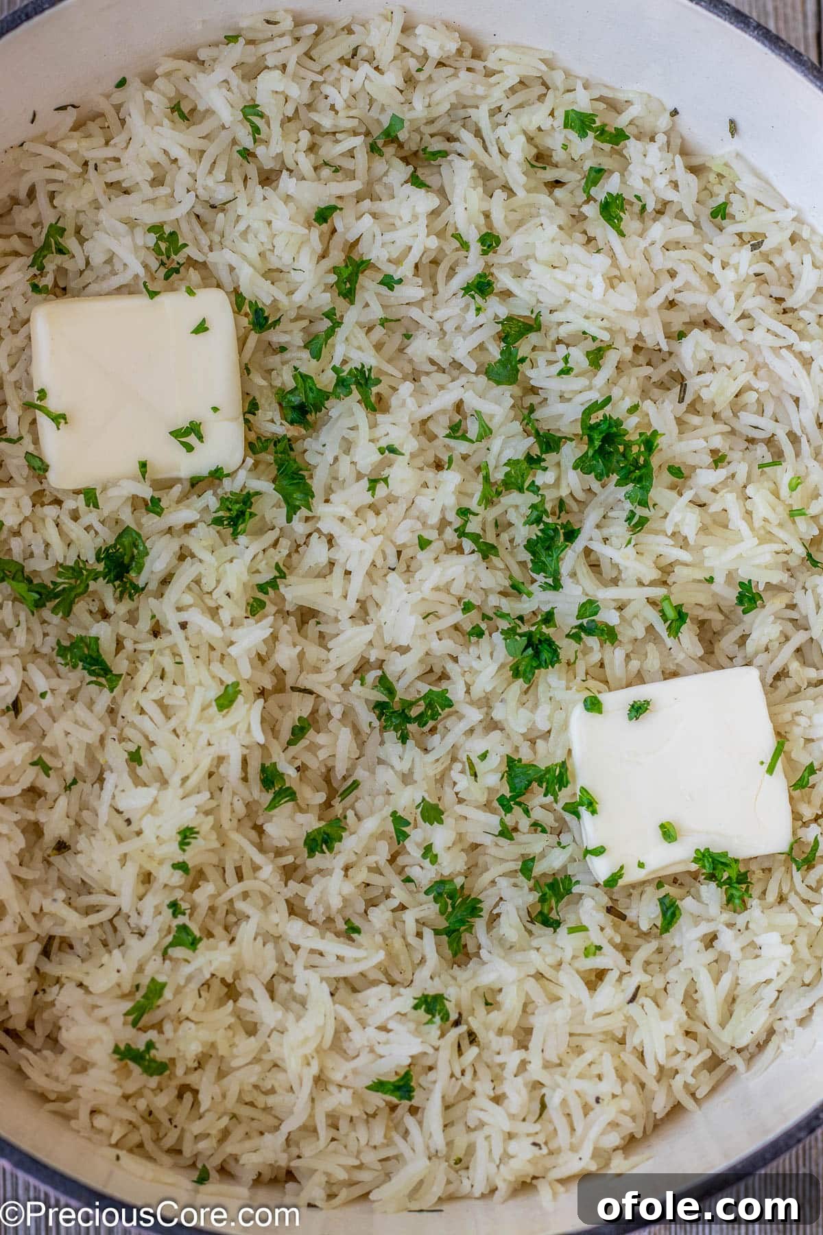 Fluffy garlic herb rice garnished with melting butter and vibrant minced parsley, ready to be fluffed and served.