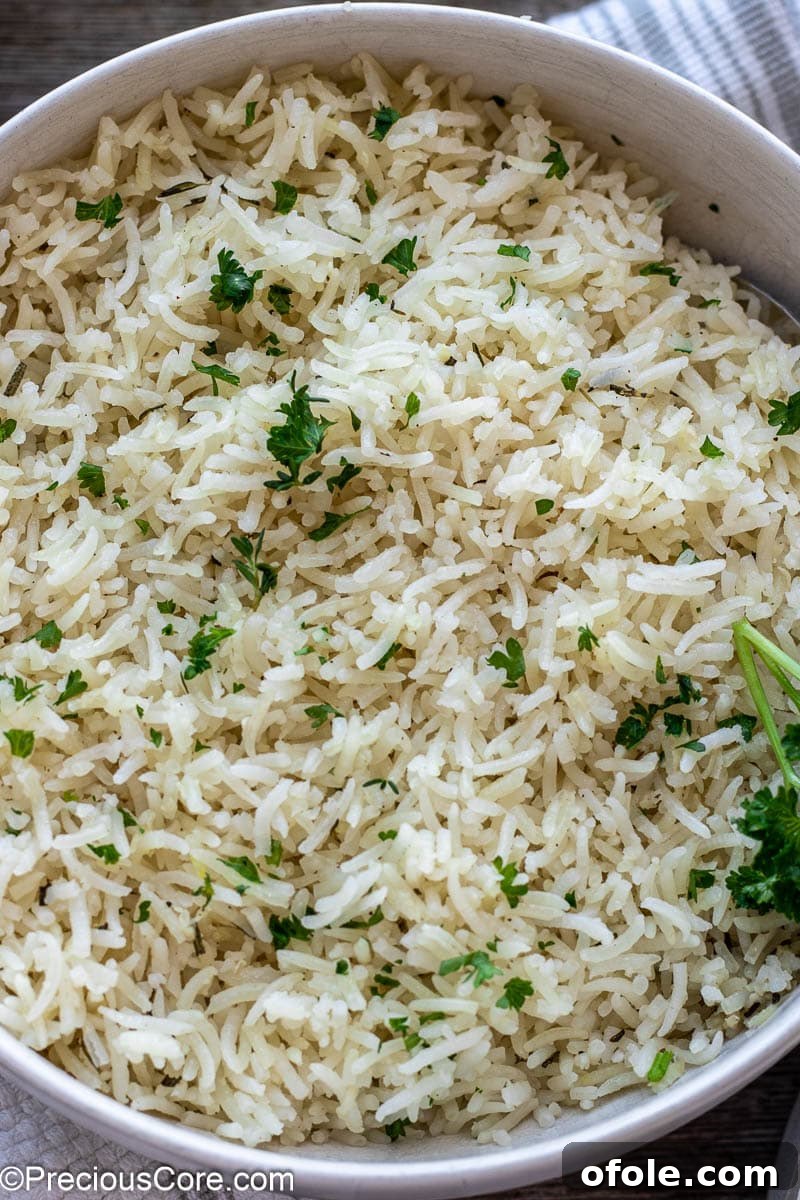 A serving of fluffy, perfectly cooked garlic herb rice in a pristine white bowl, garnished simply with a sprinkle of fresh herbs.