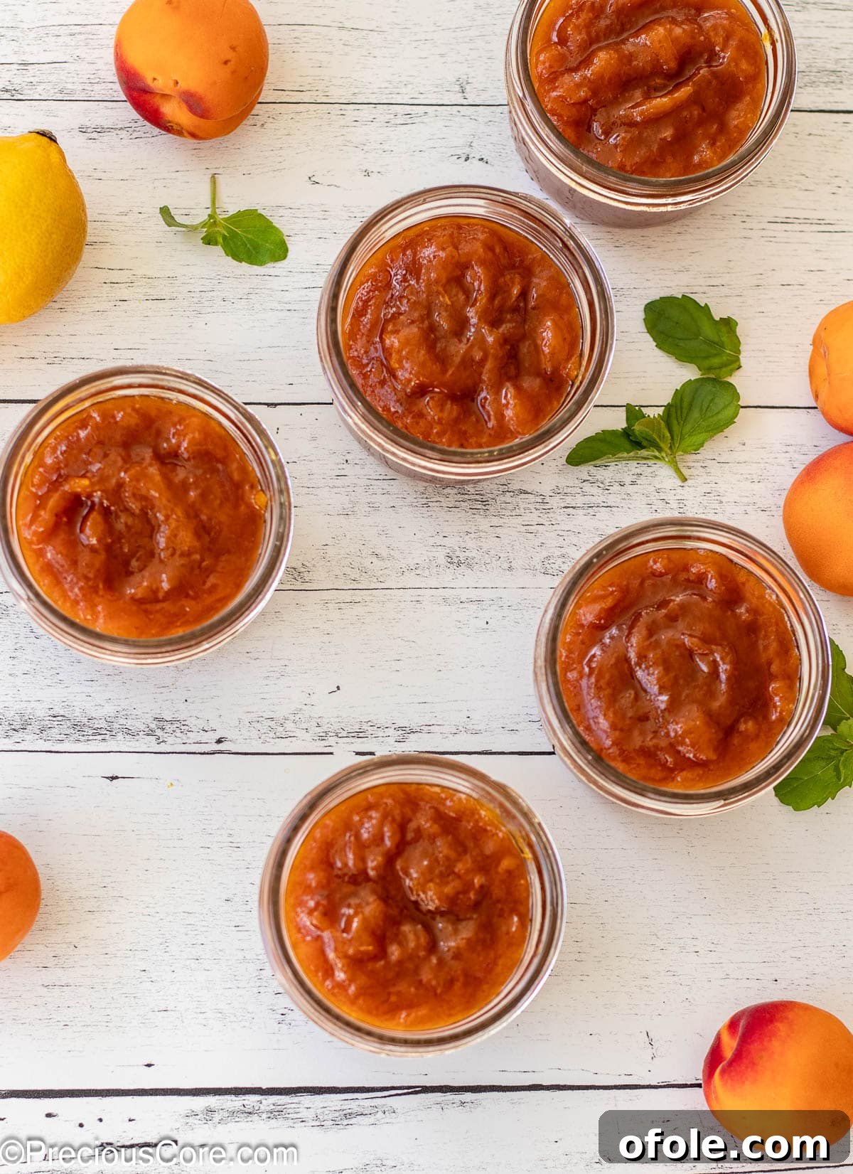 Five open mason jars, carefully filled with the golden apricot preserves, lined up on a surface, ready for sealing.
